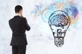 Businessman looking on light bulb with brain and cogs sketch Royalty Free Stock Photo