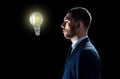 Businessman looking at lightbulb over black