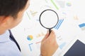 Businessman looking through magnifier glass to documents