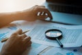 Businessman looking through a magnifying glass to documents. Business assessment and audit. Magnifying glass on a financial report