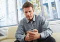 Businessman looking at mobile on sofa. Royalty Free Stock Photo