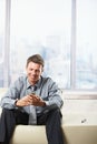 Businessman looking at mobile on sofa. Royalty Free Stock Photo