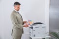 Businessman Looking At Multi Colored Paper By Color Printer Royalty Free Stock Photo