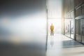 Businessman looking out of window in abstract bright light office interior with mock up place on silver wall. Success, future and Royalty Free Stock Photo