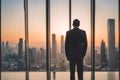 Man standing standing and looking out the large windows to skyscrapers