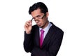 Businessman looking suspiciously at the camera, peering through his glasses with a dubious expression. Young adult latin