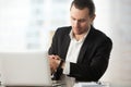 Businessman looking at wristwatch at work desk in office. Royalty Free Stock Photo