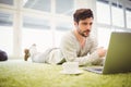 Businessman lying on carpet while using laptop in office Royalty Free Stock Photo