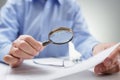 Businessman with magnifying glass reading documents