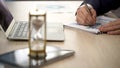 Businessman making marks on graph, sandglass standing on office desk, time Royalty Free Stock Photo