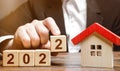 A businessman making 2022 out of blocks near house. Concept of the real estate market in the new year. Forecast of prices