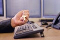 A businessman man with a religious Catholic cross in his hands is working on a computer keyboard at an office desk, close-up Royalty Free Stock Photo