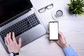 Businessman, man works at desktop on laptop and uses mobile phone. Top view, smartphone, glasses, cup of coffee. Mock up Royalty Free Stock Photo