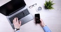 Businessman, man works at desktop on laptop and uses mobile phone. Top view, smartphone, glasses, cup of coffee. Mock up Royalty Free Stock Photo