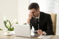 Businessman massaging nose bridge, holding glasses, eye strain,