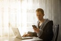 Businessman in medical mask and in a home bathrobe during quarantine work in cafe . A young man in a cafe works at a laptop by the Royalty Free Stock Photo