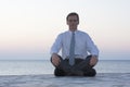 Businessman meditating by the sea