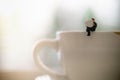 Businessman miniature figure sitting and reading a newspaper on dirty cup of hot coffee with copy scape