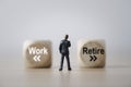Businessman miniature figure standing and thinking to consider to select between work and retire concept Royalty Free Stock Photo
