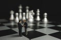 Businessman miniature handshake on chessboard with silver chess background.