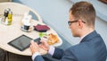 Businessman with mobile phone during breakfast.