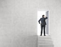 Businessman near open door in concrete wall with stairs Royalty Free Stock Photo