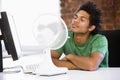 Businessman in office with computer and fan