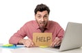 Businessman at office desk working on computer laptop asking for help holding cardboard sign looking sad and depressed Royalty Free Stock Photo