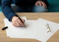 Businessman in the office writes a letter or signs a document on a piece of white paper with a fountain pen with nib. Royalty Free Stock Photo