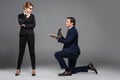 businessman on one knee holding laptop for feminist businesswoman