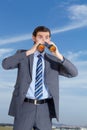 Businessman, outdoor with binoculars and suit, looking and corporate wear against blue sky. Young man, searching for