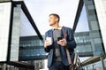 Businessman outside building with phone, coffee and bag, happy waiting for online taxi service after work. Office Royalty Free Stock Photo