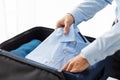 Businessman packing clothes into travel bag