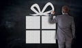 Businessman paints gift on blackboard concept