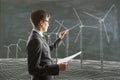 Businessman paints wind generators on the blackboard and carries