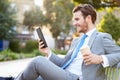 Businessman On Park Bench With Coffee Using Digital Tablet