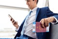 Businessman With Passport And Boarding Pass Sitting In Airport Departure Lounge Using Mobile Phone Royalty Free Stock Photo