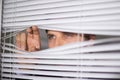 Businessman peeking through blinds in office