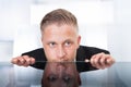 Businessman peering furtively over the top of his desk Royalty Free Stock Photo