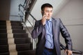 Businessman with phone in his hand makes call while on stairs at office building during break, wearing suit. Business Royalty Free Stock Photo