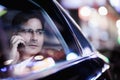 Businessman on the phone and looking out the car window at night, reflected lights Royalty Free Stock Photo