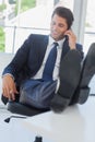 Businessman on the phone relaxing with his feet on his desk