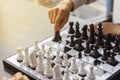 A businessman picking up a black chess piece.