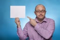 A businessman in a piked shirt holds a blank, white sign, placeholder