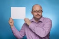 A businessman in a piked shirt holds a blank, white sign, placeholder