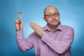 A businessman in a piked shirt pointing with the hand on a crucifix