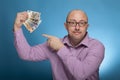 A businessman in a piked shirt pointing with the index finger on euro cash