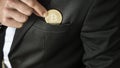 Businessman placing a Bitcoin in his pocket
