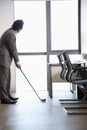 Businessman playing golf in his office, holding golf club