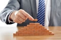 Businessman playing with wooden domino figures - the concept of success and growth Royalty Free Stock Photo